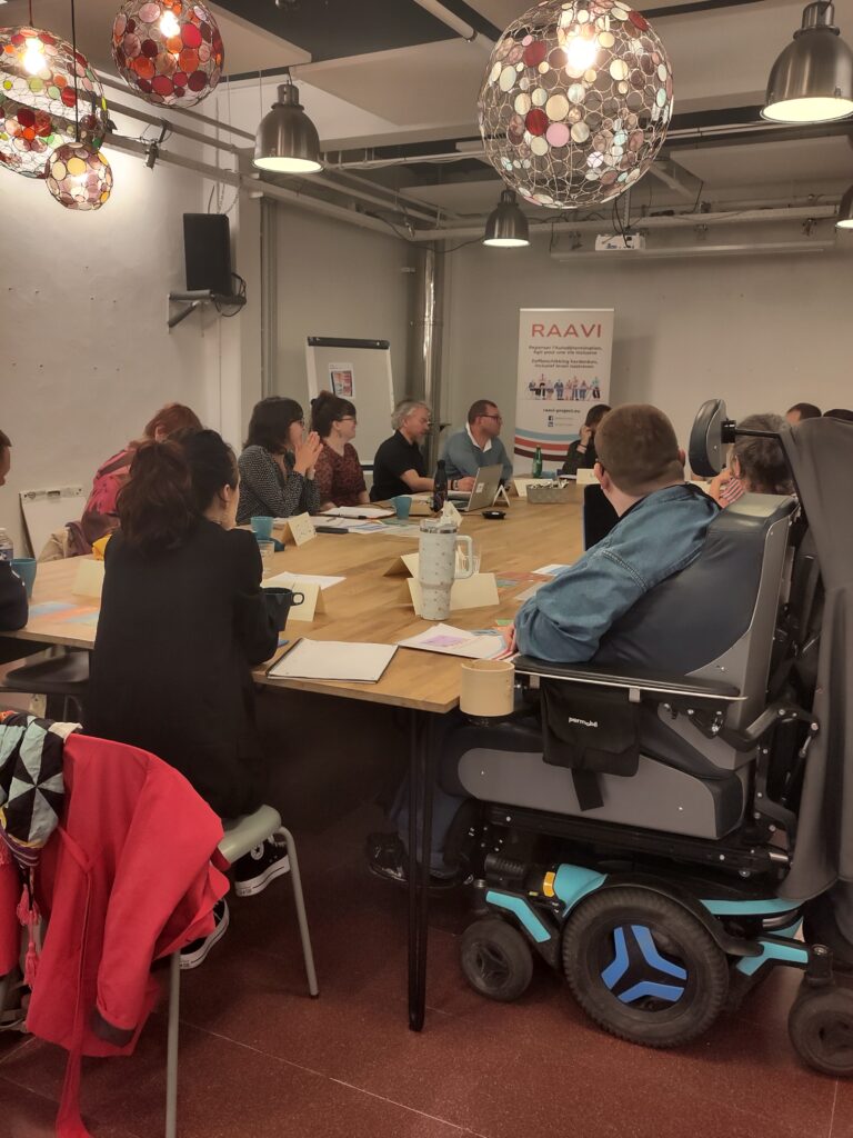 Participants et participantes à la journée introductive des ateliers RAAVI qui s'est tenue à Bruxelles. Tous assis autour d'une table.